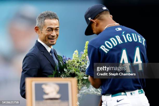 Former Seattle Mariner Ichiro Suzuki receives flowers from Julio Rodriguez of the Seattle Mariners during the Mariners Hall of Fame pregame ceremony...