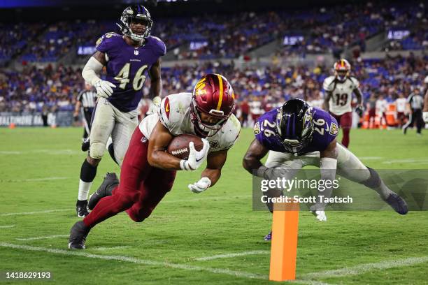 Reggie Bonnafon of the Washington Commanders scores a touchdown in front of Josh Ross and Geno Stone of the Baltimore Ravens during the second half...