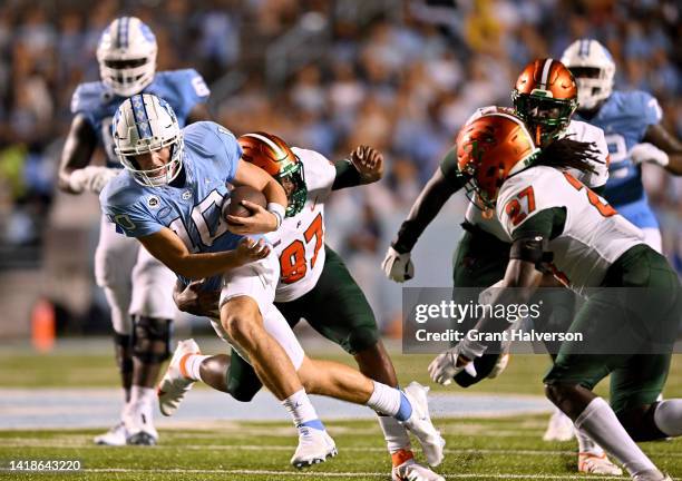 Drake Maye of the North Carolina Tar Heels scrambles under pressure from Kamari Stephens of the Florida A&M Rattlers during the second half of their...