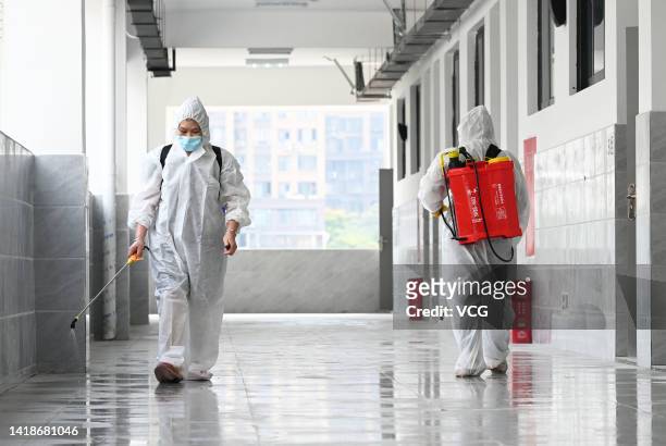 Aerial view of staff members wearing personal protective equipment disinfecting a corridor of a primary school before a new semester on August 28,...