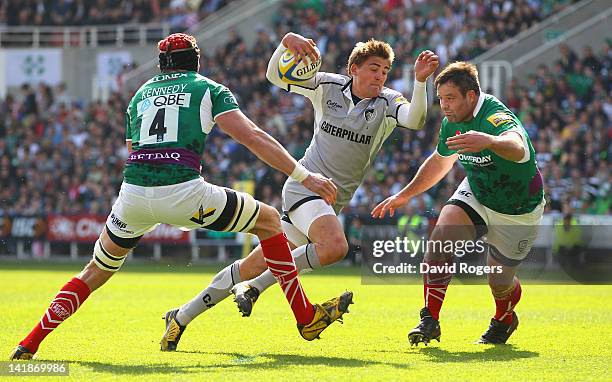 Toby Flood of Leicester breaks away from the tackle from Nick Kennedy and Faan Rautenbach during the Aviva Premiership match between London Irish and...