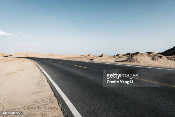 wide and low angle view of asphalt road in gobi desert - wide sky stock pictures, royalty-free photos & images