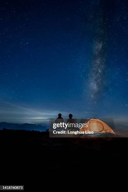 two people under the stars at night - zelt nacht stock-fotos und bilder