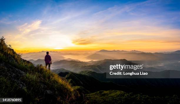 a grown woman standing on a mountain at sunrise - salida del sol fotografías e imágenes de stock