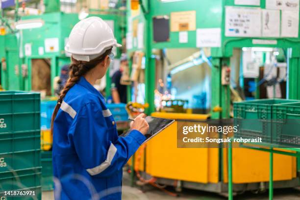 a female worker inspecting the work of a robot in a factory. - car exports stock-fotos und bilder