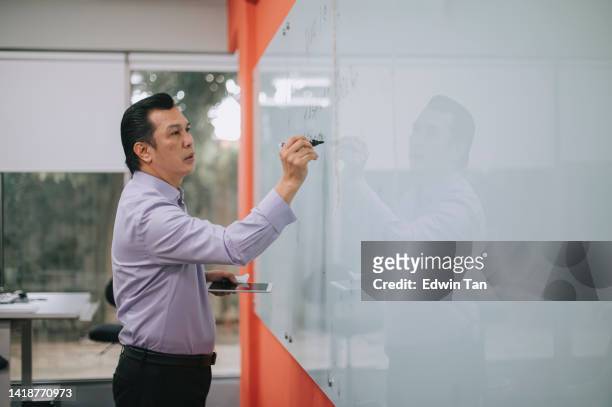 asian malay professor giving lecture writing on whiteboard in classroom explaining - lecturer whiteboard stock pictures, royalty-free photos & images