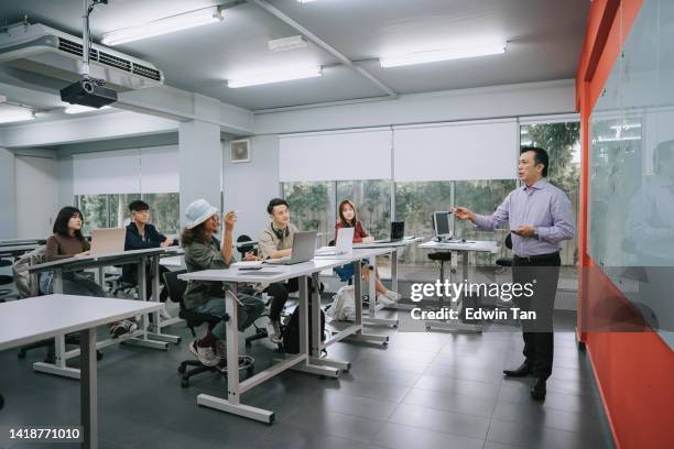 asiatischer malaiischer college-dozent, der erwachsene studentenfragen im klassenzimmer beantwortet - chinese tutor study stock-fotos und bilder