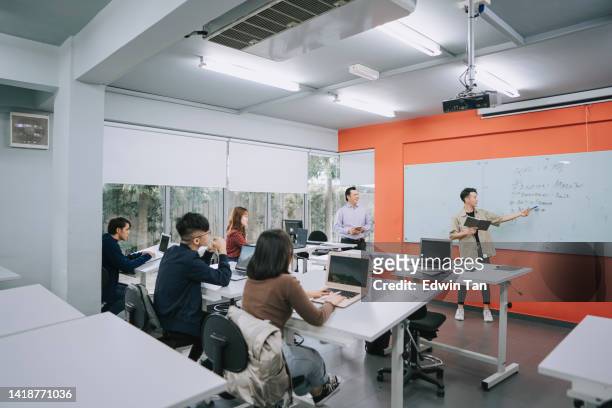 asiatischer chinesischer college-junger, der auf whiteboard zeigt und seinem klassenkameraden und dozenten im klassenzimmer erklärt - chinese tutor study stock-fotos und bilder