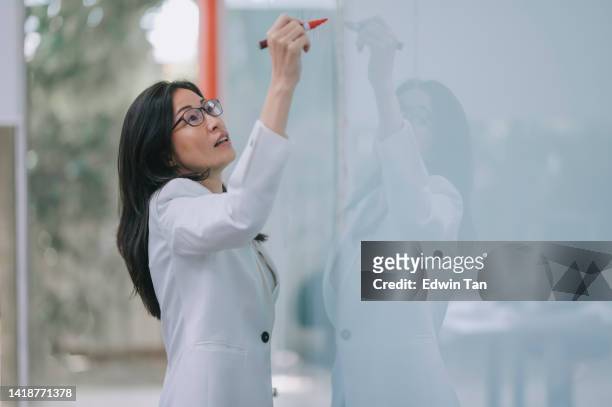 asian chinese female lecturer writing on whiteboard in classroom explaining to her student - lecturer whiteboard stock pictures, royalty-free photos & images