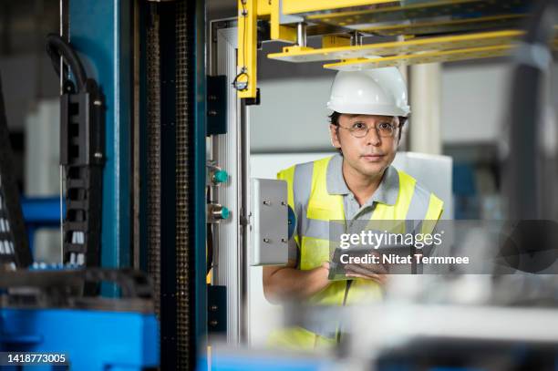 cutting and strapping the lead ingot extrusion process. middle-aged japanese engineers use a tablet computer to review the cutting and strapping process of lead ingot cutting machines in a production line. - aluminium ingots stockfoto's en -beelden