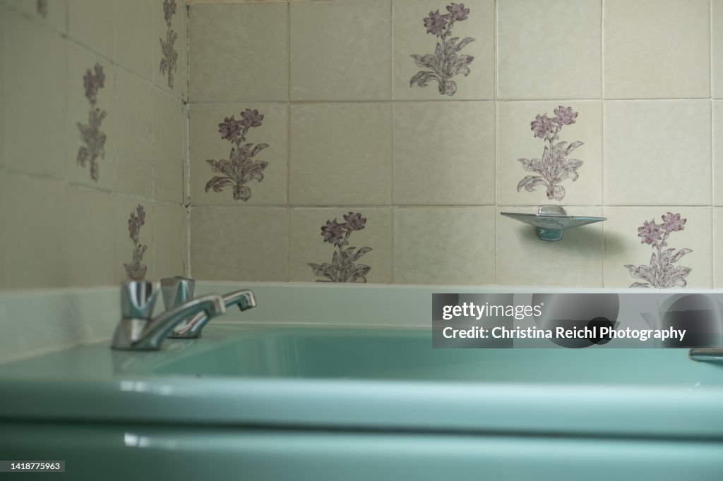 Old, turquoise bathtub in vintage bathroom