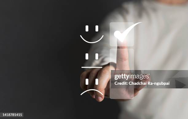 finger of customer touching and check mark icon face emoticon smile on dark background, service mind, service rating. satisfaction and customer service concept - lealdade imagens e fotografias de stock