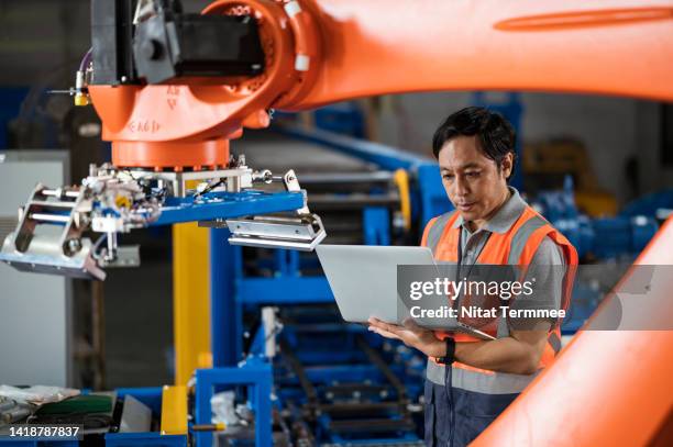 robot programming of the lead ingot palletizing solution. a japanese software engineers use a laptop computer to input sequence control configurations to reduce lead times and set-up costs for car battery manufacturing processes. - battery manufacturing stock pictures, royalty-free photos & images