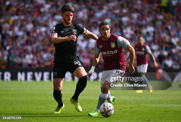 Emi Buendia of Aston Villa runs with the ball whilst under pressure from Declan Rice of West Ham United during the Premier League match between Aston...