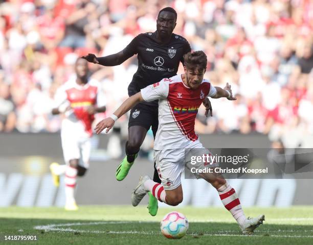 Jan Thielmann of 1. FC Koeln runs with the ball whilst under pressure from Silas Katompa Mvumpa of VfB Stuttgart during the Bundesliga match between...