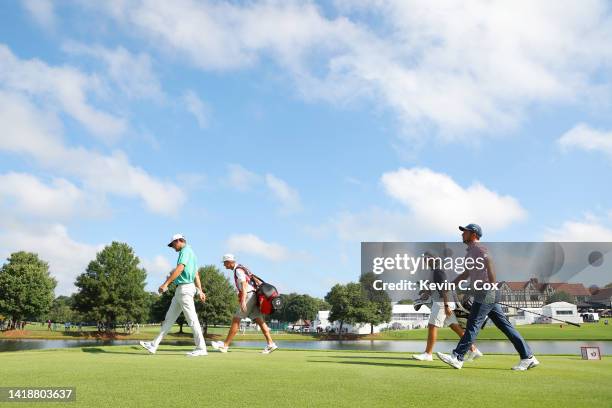 Scottie Scheffler of the United States and Xander Schauffele of the United States walk from the 16th tee during the continuation of the weather...