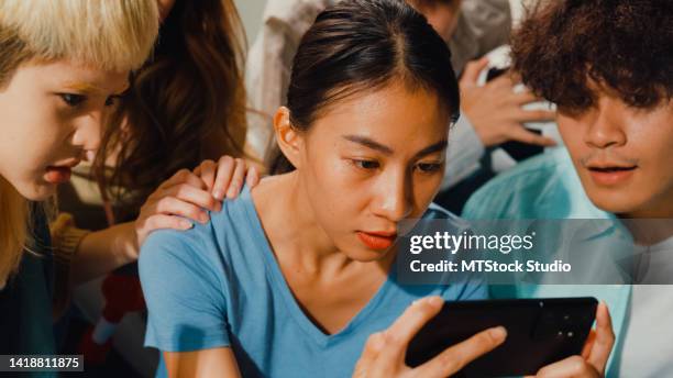 close-up group of happy asian teenage people sit on couch watch cheer sport soccer games world cup championship together on smartphone. - best female performance stock pictures, royalty-free photos & images