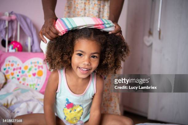 beautiful and happy girl looking at camera, while her mother is helping her get dressed - mother and daughter making the bed stock pictures, royalty-free photos & images