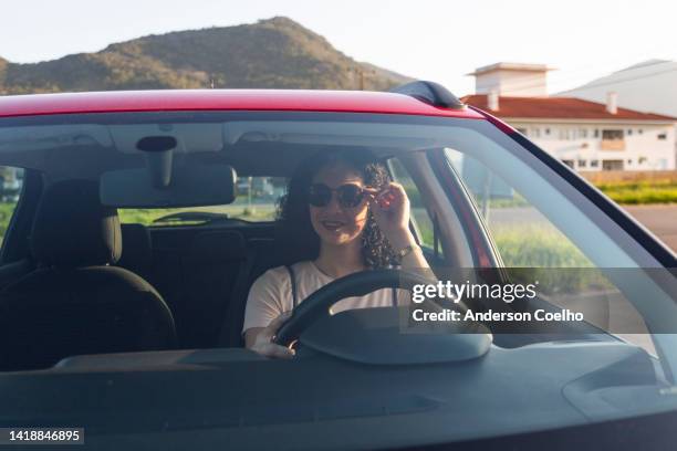 donna che regola gli occhiali da sole all'interno dell'automobile - specchietto di veicolo foto e immagini stock