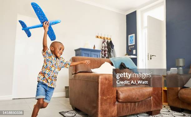 cute little african boy running with toy airplane at home - model airplane stock pictures, royalty-free photos & images