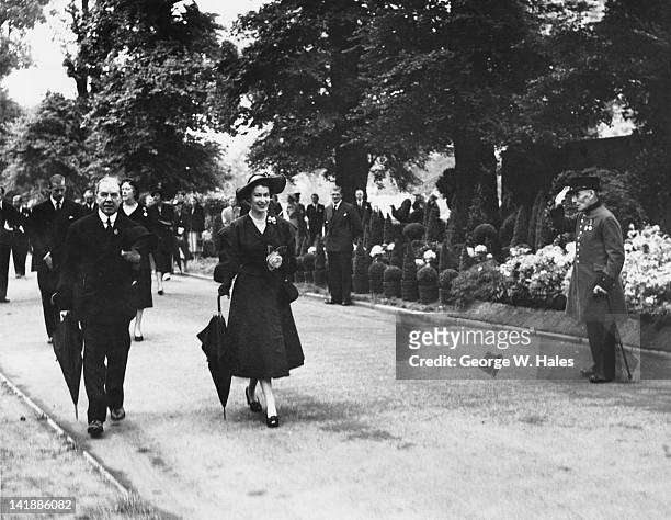 Chelsea pensioner salutes Queen Elizabeth II as she tours the Chelsea Flower Show, London, 20th May 1952. The Queen is accompanied by Henry McLaren,...