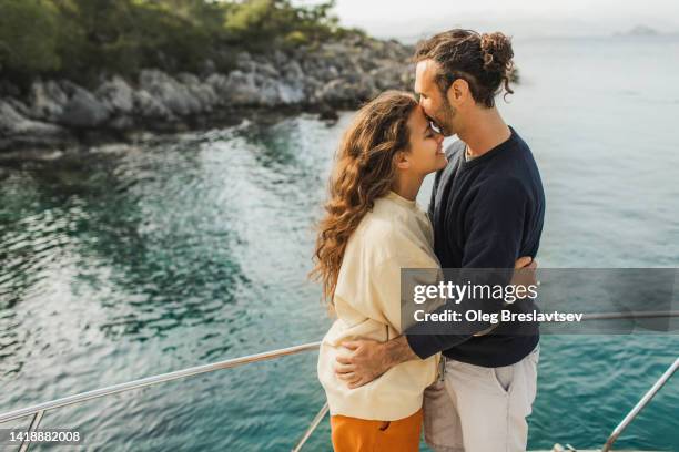 pretty couple kissing on board of yacht at sunset. love and sunshine. honeymoon and vacations together - kiss booth stock-fotos und bilder