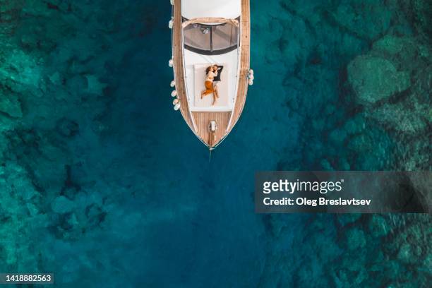 aerial drone view of couple in love on board of luxury yacht anchored in tropical paradise bay with emerald clear water - capital fotografías e imágenes de stock