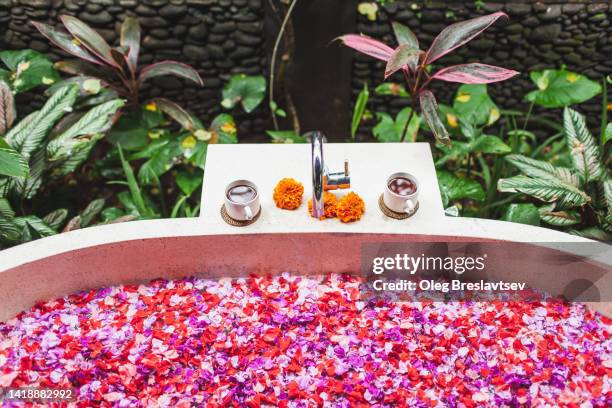 stone bath tub full of flower petals in balinese relaxation spa. wellness and vitality - bali spa stock pictures, royalty-free photos & images