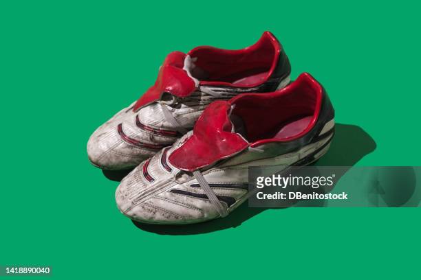 used and stained white and red football boots on green background. concept of soccer, world cup, sport, qatar and sports shoes. - soccer boot stock pictures, royalty-free photos & images
