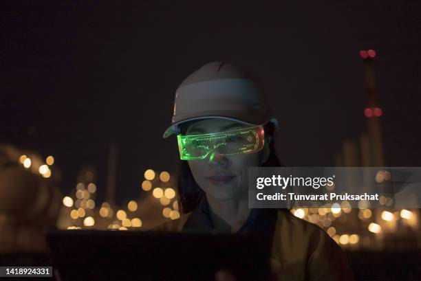 woman wearing mixed reality smart glasses at project petrochemical site night shift . - hands free apparaat stockfoto's en -beelden