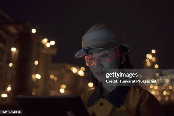 woman wearing mixed reality smart glasses at project petrochemical site night shift . - hands free apparaat stockfoto's en -beelden