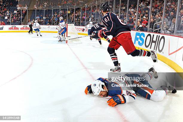 Rick Nash of the Columbus Blue Jackets skates away as Theo Peckham of the Edmonton Oilers lies on the ice after being checked by Nash during the...