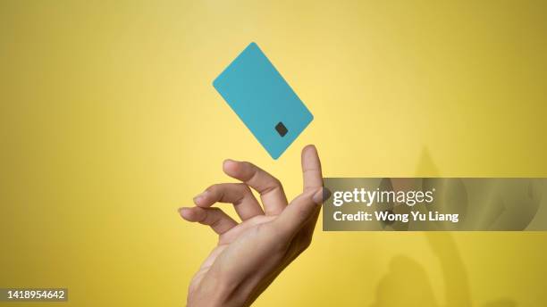 close up male hand and levitating template mockup bank credit card with online service yellow background - credit fotografías e imágenes de stock