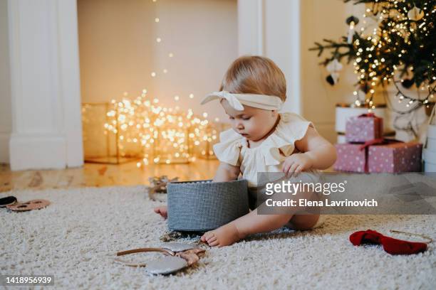 little cute girl opens christmas gifts. christmas concept. beautiful christmas interior - baby christmas stock-fotos und bilder
