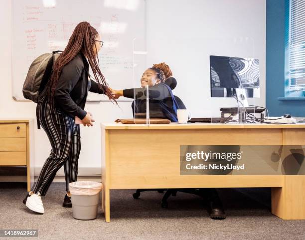 young woman greeting with fist bump to a colleague in office - farewell colleague stock pictures, royalty-free photos & images