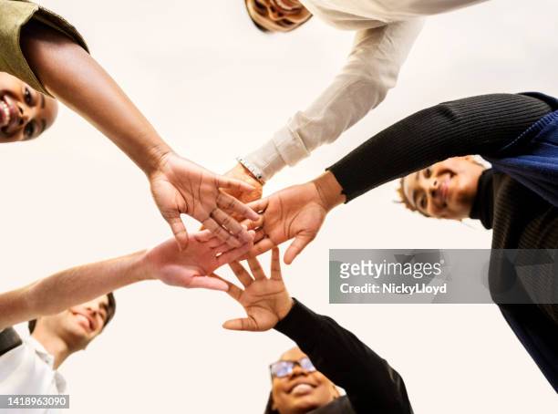 business people putting their hands together showing teamwork and unity - hand stack stock pictures, royalty-free photos & images