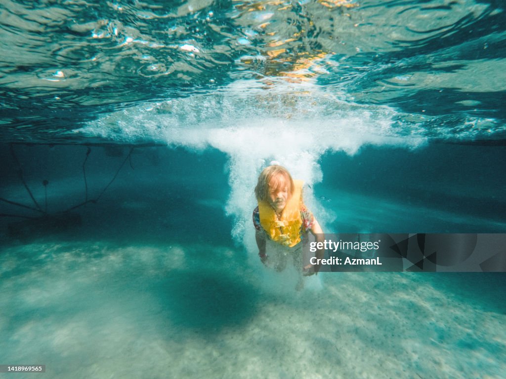 Young Kid Jumping And Swimming Underwater While On Summer Holidays