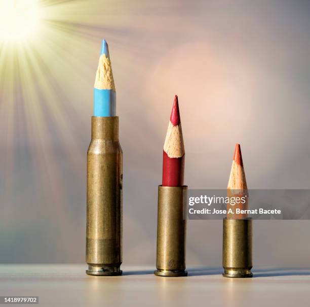 bullet casings and children's colored pencils illuminated by rays of sunlight. - crimine con arma da fuoco foto e immagini stock