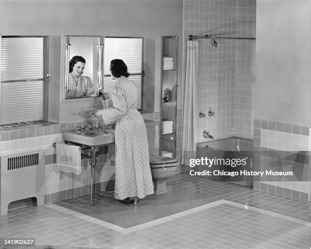 Furniture Settings & Home Interiors display, Bathroom, woman with a curling iron , Chicago, Illinois, June 10, 1946.