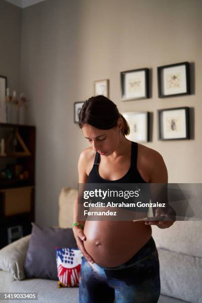 pregnant woman standing with cell phone. - tummy time stock pictures, royalty-free photos & images