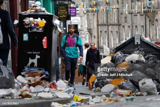 Members of the public walk past a large piles of rubbish on August 29, 2022 in Edinburgh, Scotland. Bin collections have been suspended in the...