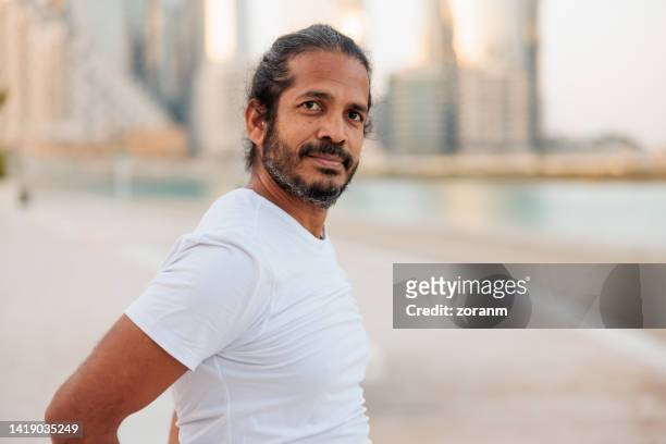 bearded man in white t-shirt standing on the pier and looking at camera - yoga office arab stock pictures, royalty-free photos & images