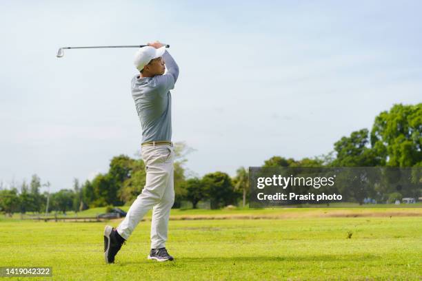 asian man golfer hitting golf ball along fairway with iron driver - tee off fotografías e imágenes de stock