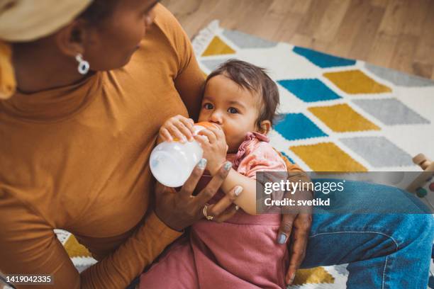 young mother with baby at home - baby bottle stock pictures, royalty-free photos & images