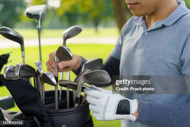 cropped photo of asian golf player man reaching for an iron club in a leather bag - bolsa de golf fotografías e imágenes de stock