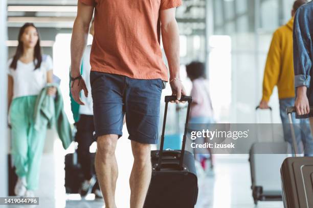 passengers walking with luggage at airport - shorts stock pictures, royalty-free photos & images