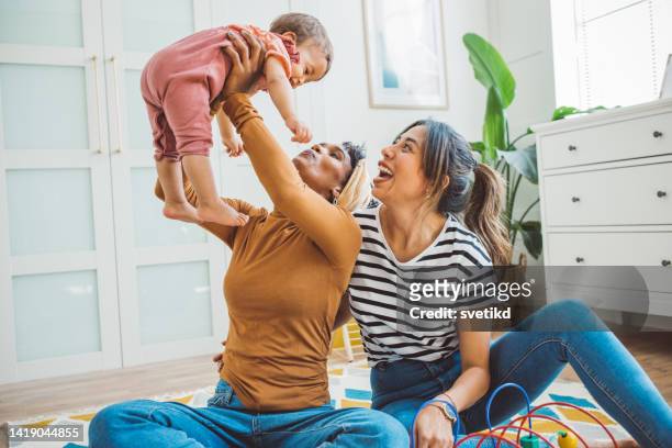 gay couple with baby at home - lesbian stockfoto's en -beelden