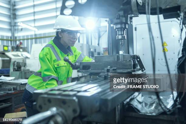 female engineer working on a lathe by forming parts in the automotive industry by working intentionally with protective equipment high security - workers compensation - fotografias e filmes do acervo