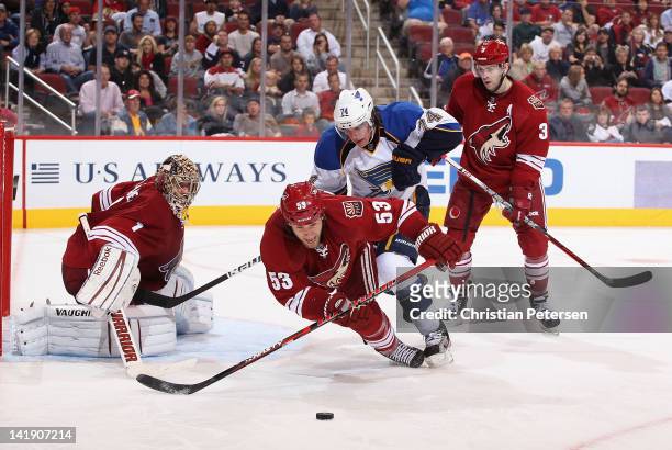 Derek Morris of the Phoenix Coyotes is checked by T.J. Oshie of the St Louis Blues as he attempts to clear the puck during the NHL game at Jobing.com...