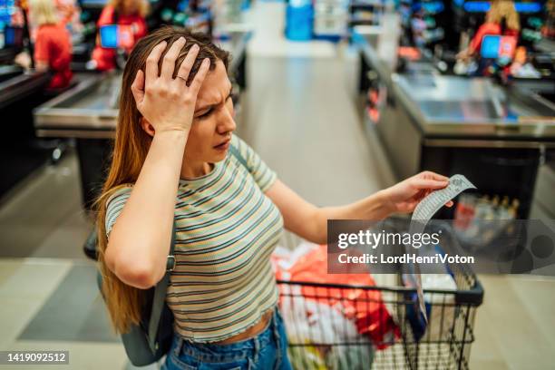 woman feeling concerned about grocery prices on the bill - shopping disappointment stock pictures, royalty-free photos & images